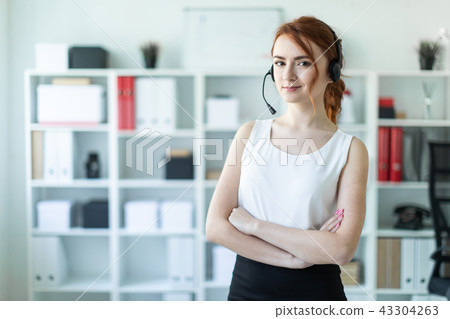 Beautiful young girl in headphones with microphone standing in office. 43304263