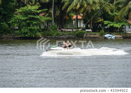 Happy young couple having fun riding on a jet ski Happy young couple having fun riding on a jet ski 43304922