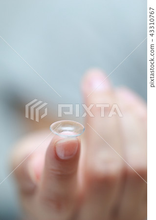 Female fingers wearing contact lenses Female fingers wearing contact lenses 43310767