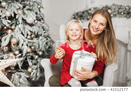 Mother and her daughters opening the little girl's birthday present 43312577