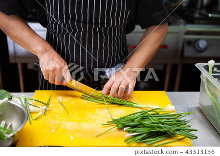 Chef using knife slice Scallions or Spring onion.  43313136