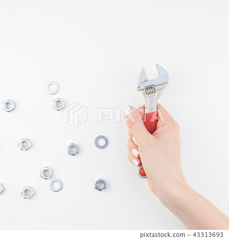 Female hand holding spanner on white background 43313693