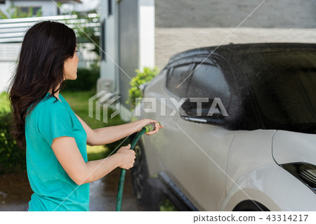 woman water spray her car with water tube washing it 43314217