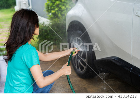woman water spray her car wheel with water tube washing it 43314218