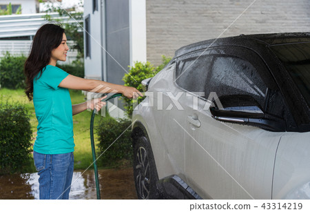 woman water spray her car with water tube washing it 43314219