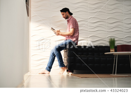 Young Hispanic Man Watching Movie On Tablet Computer 43324023