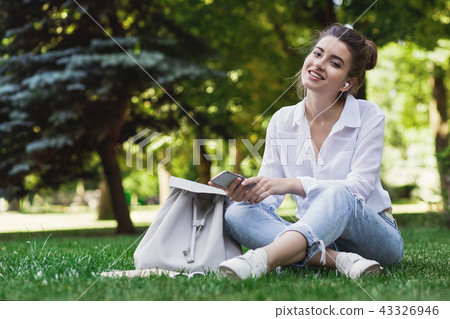 Happy woman listening to music in park 43326946