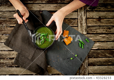 Women's hands, holding a spoon, eating soup with green vegetables.Vegetarian simple food Women's hands, holding a spoon, eating soup with green vegetables.Vegetarian simple food 43328233