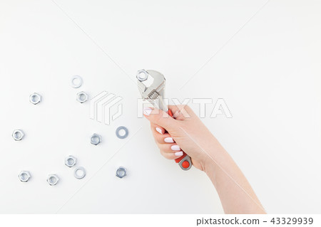 Female hand holding spanner on white background Female hand holding spanner on white background 43329939