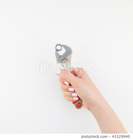 Female hand holding spanner on white background Female hand holding spanner on white background 43329940