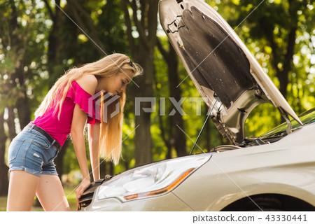 Attractive girl look in open car hood 43330441