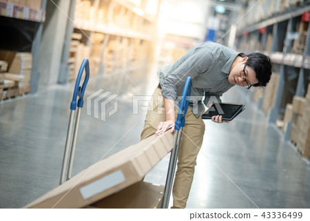 Asian man doing stocktaking on tablet in warehouse Asian man doing stocktaking on tablet in warehouse 43336499