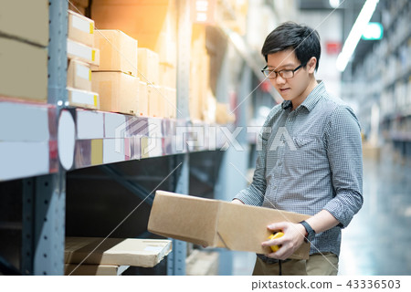Asian man carrying cardboard box in warehouse 43336503
