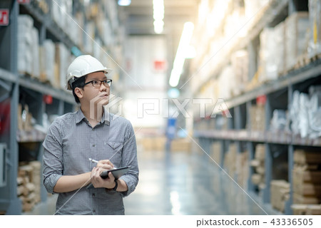 Asian man doing stocktaking on tablet in warehouse 43336505