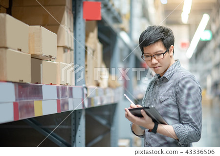 Asian man doing stocktaking on tablet in warehouse 43336506