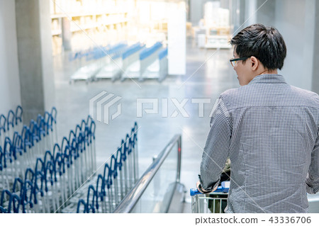 Asian man holding shopping cart on travelator 43336706