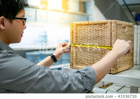 Asian man using tape measure on wooden woven box Asian man using tape measure on wooden woven box 43336730
