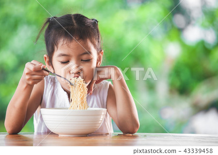 asian child girl eating delicious instant noodles asian child girl eating delicious instant noodles 43339458