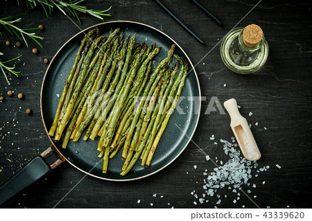asparagus in a pan on a wooden black table with rosemary salt and olive oil asparagus in a pan on a wooden black table with rosemary salt and olive oil 43339620