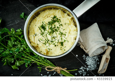 creamy puree of potatoes sprinkled with parsley in a silver pot on a black table 43339915