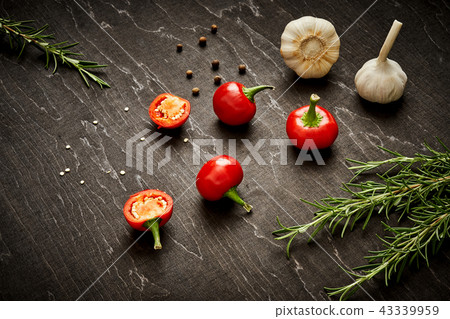 spicy red peppers, garlic and rosemary on a black wooden table spicy red peppers, garlic and rosemary on a black wooden table 43339959