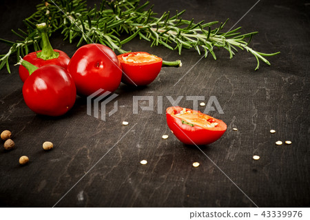 fresh and spicy red peppers and rosemary on a black table fresh and spicy red peppers and rosemary on a black table 43339976