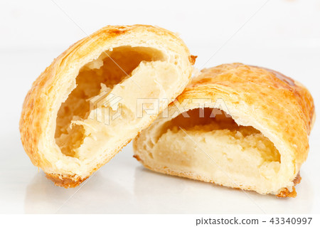 Tasty puff pastry dessert cut in half . Delicious pastries with potatoes on light background. 43340997