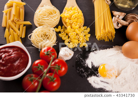 Four types of raw uncooked pasta next to tomatoe souce 43341730