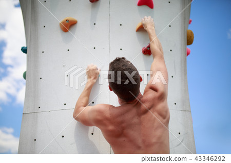 Photo from back of sporty man climbing on boulder Photo from back of sporty man climbing on boulder 43346292