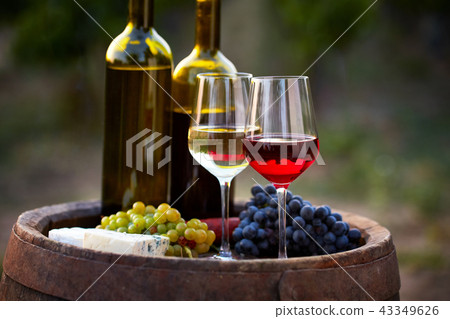 Pair of wine glasses and bottles on old barrel 43349626