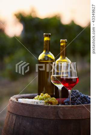 Pair of wine glasses and bottles on old barrel Pair of wine glasses and bottles on old barrel 43349627