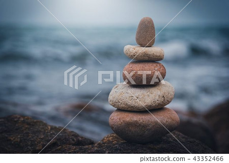 Stone tower on the rock near pebble beach. Stone tower on the rock near pebble beach. 43352466