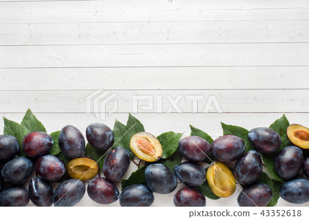 Fresh plum fruit with leaves on a light table Fresh plum fruit with leaves on a light table 43352618