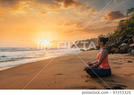 Woman doing yoga at beach - Padmasana lotus pose 43353320