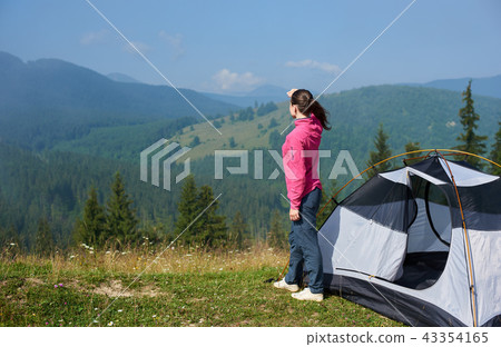 Young woman having a rest near tourist tent in the summer morning in the mountains 43354165