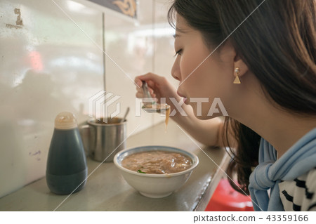 asian visitor trying to eat hot food. asian visitor trying to eat hot food. 43359166