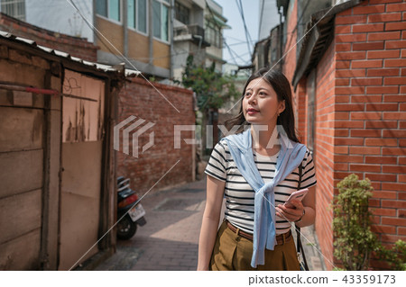 visitor strolling in the alley by holing a phone. visitor strolling in the alley by holing a phone. 43359173