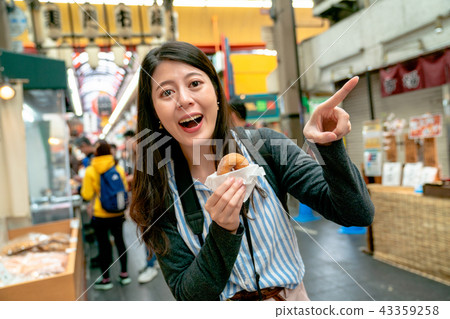 asian woman holding the dessert in one hand. 43359258