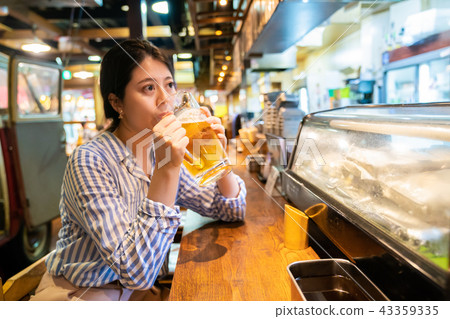 asian woman drinking at the counter of izakaya. 43359335