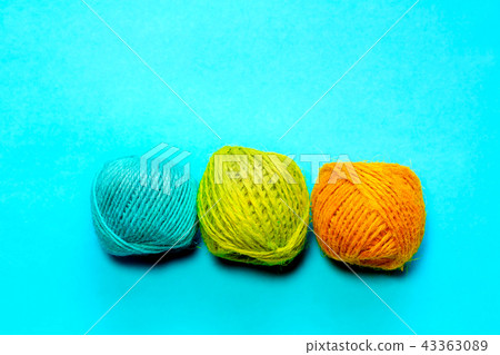 黃色和藍色和橙色毛線被安置在藍色背景下 黃色和藍色和橙色毛線被安置在藍色背景下 43363089