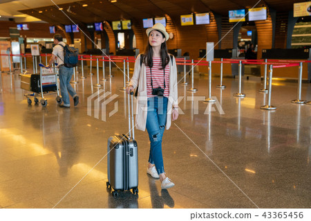 asian visitor walking in the hall. carrying luggage in airport. 43365456