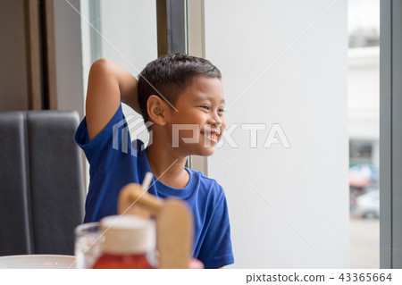 Cute asian boy seat at window eating food 43365664