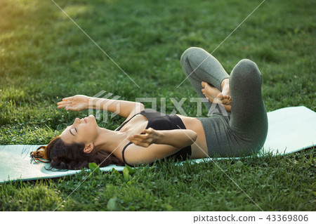 Funny photo about young woman doing yoga exercise and fooling around outdoors in park at morning. 43369806