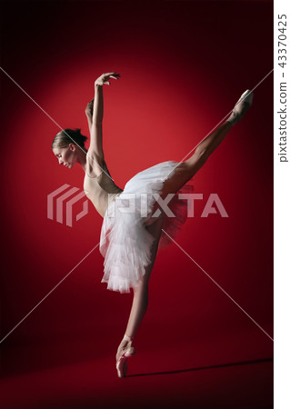 Ballerina. Young graceful female ballet dancer dancing at red studioskill. Beauty of classic ballet. 43370425
