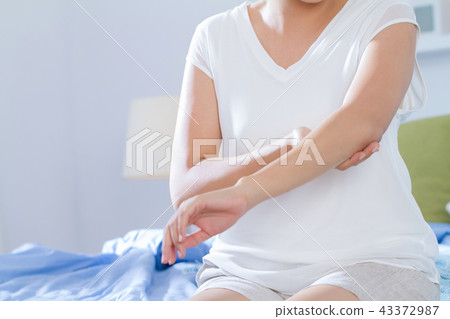 young woman applying beauty lotion on her elbow 43372987