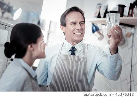 Professional waiter looking at eh glass while standing next to his colleague 43376318