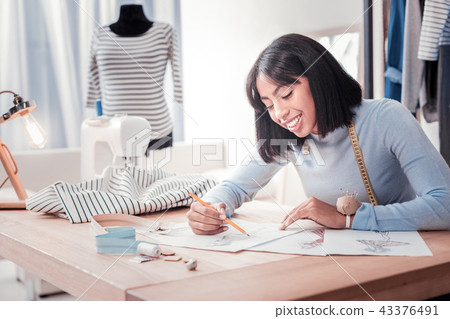 Pleased designer drawing sketches for new dresses 43376491