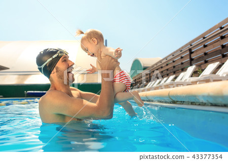 Happy family having fun by the swimming pool Happy family having fun by the swimming pool 43377354