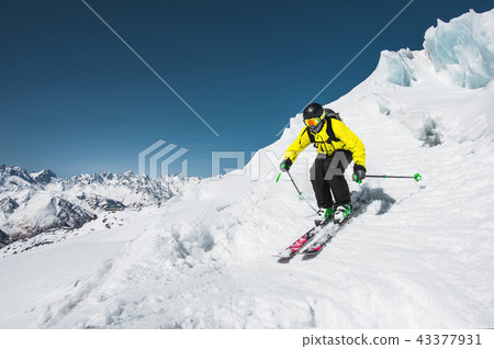 Professional skier at the speed before jumping from the glacier in winter against the blue sky and Professional skier at the speed before jumping from the glacier in winter against the blue sky and 43377931