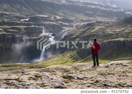 Tourist looks at a waterfall in Iceland 43378792